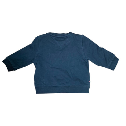 Back view of a black Amare Tutto Tommy tracksuit sweatshirt with ribbed cuffs and hem on a wooden floor.