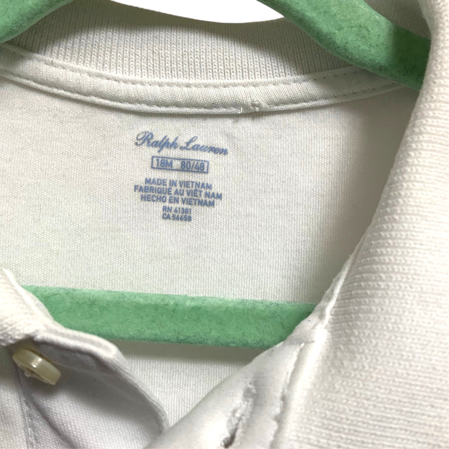 Amare Tutto pre-owned white Ralph Lauren baby polo shirt size 18M label detail on a green hanger